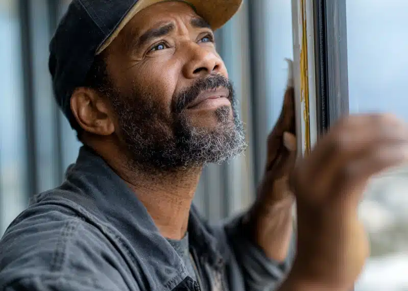 handyman inspecting weatherstripping on a window
